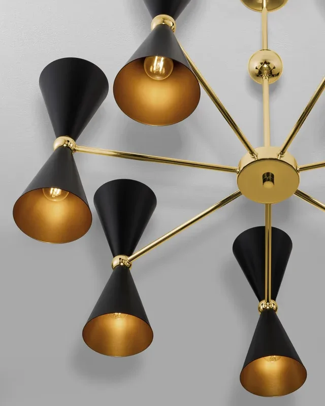 Decorative gold chandelier with black conical lampshades extending from a central hub against a gray wall, modern lighting fixture design