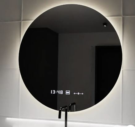 Round backlit bathroom mirror above a sink, with a digital clock showing 13:48 and small icons on the display.