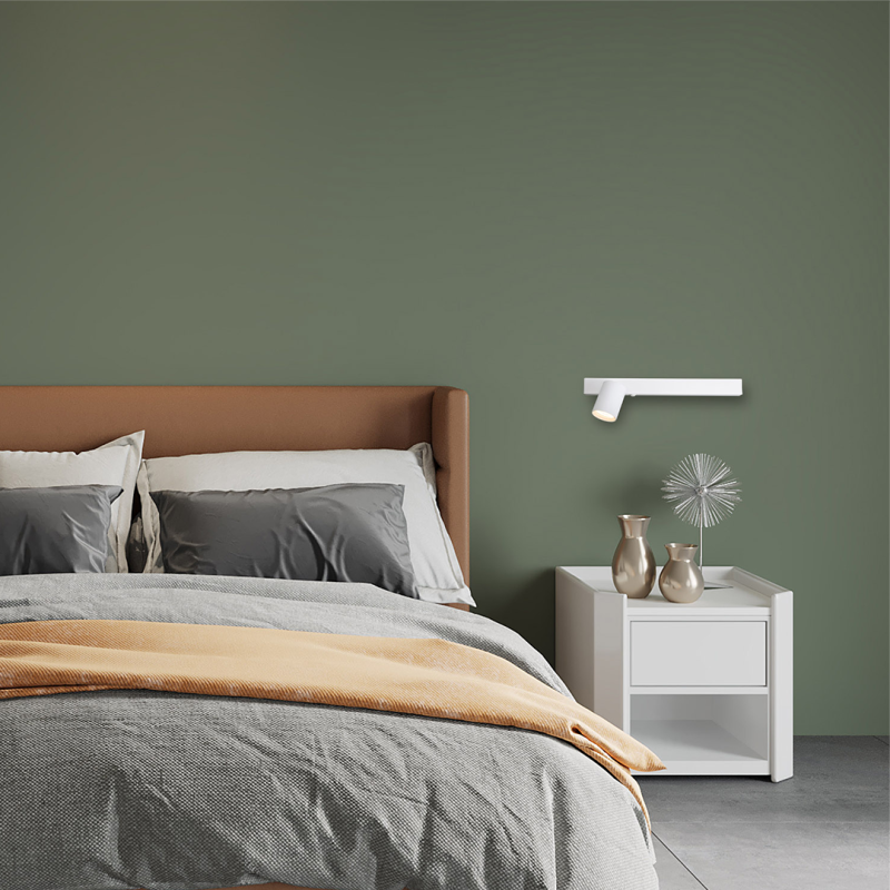 Modern bedroom with olive green wall, brown upholstered headboard, gray bedding, and white nightstand with gold vases.