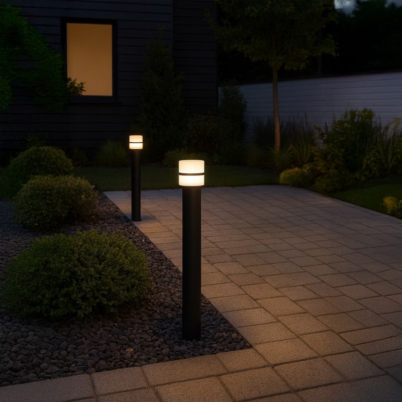 Night scene of a paved walkway with three illuminated bollard lights guiding a garden path.