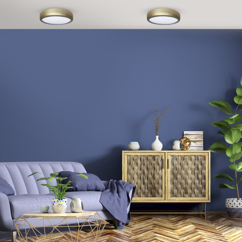 Living room with a blue accent wall, a light purple sofa, a geometric gold coffee table, and a wooden cabinet with vases and decor items.