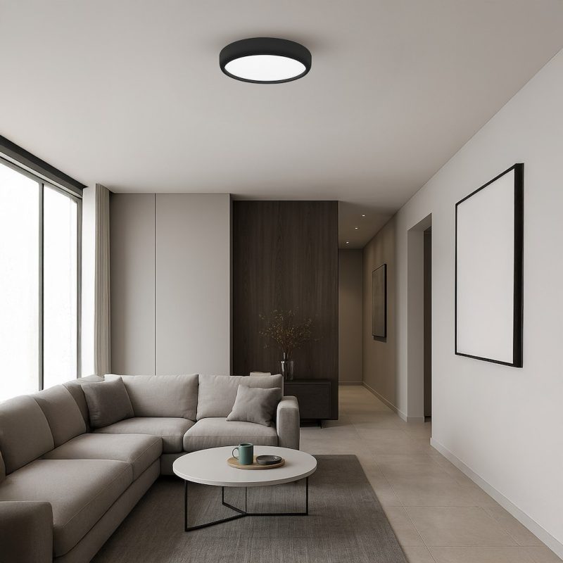 Modern living room with a light gray L-shaped sofa, round white coffee table, and large window letting in daylight.