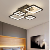 Contemporary ceiling light with interlocking square rings, illuminating a bedroom with a gray cabinet wall and wooden headboard.