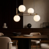 Modern dining room with a round chandelier of four globe lights over a wooden table.