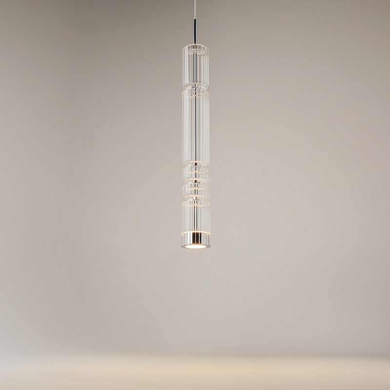 Clear glass pendant light hanging from a ceiling, with stacked rings and a cylindrical shape against a neutral background.