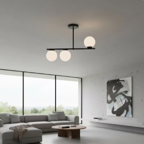 Modern living room with large windows, grey sectional sofa, round wooden coffee table, abstract wall art, and a three-globe ceiling light.