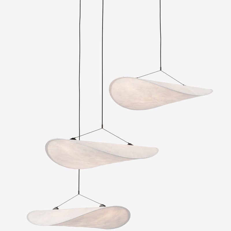 Three sculptural white wing-shaped pendant lights suspended by black cords from the ceiling in a staggered arrangement.