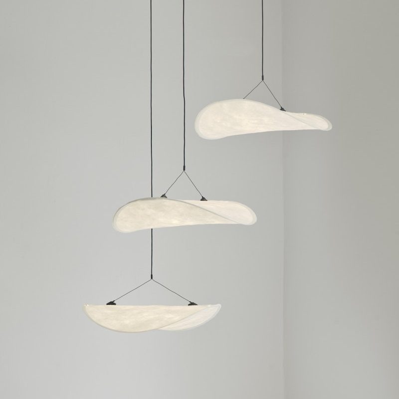 Three crescent-shaped white pendant lights hanging at varying heights from black cords.