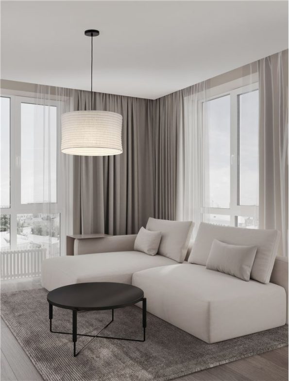 Bright contemporary living room with a white L-shaped sofa, gray cushions, and a round black coffee table on a gray rug by large windows and sheer curtains.