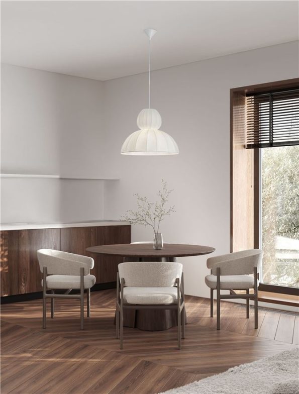 Modern dining room with a round wooden table, four upholstered chairs, a white pendant light, and a vase with branches; large window on the right.