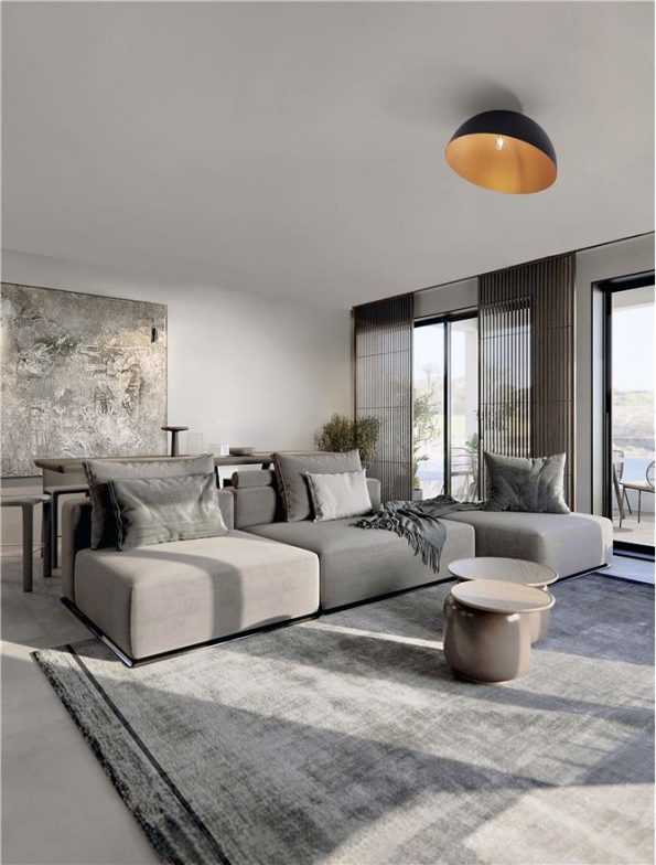 Modern gray sectional sofa in a bright open-plan living room with a large rug and floor-to-ceiling windows on the right edge.”,