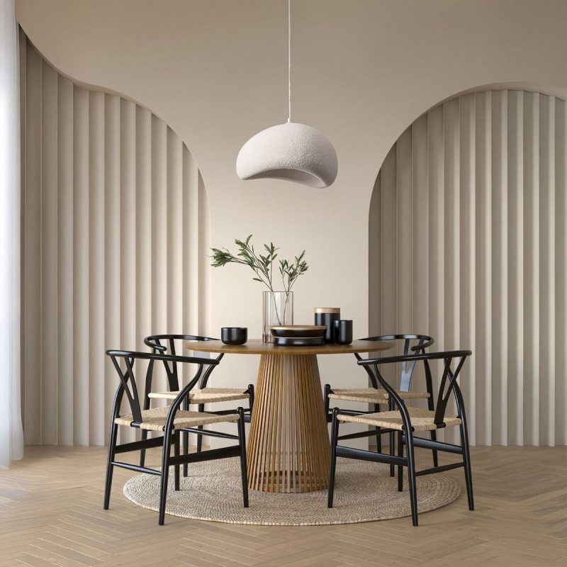 Modern dining area with a round wooden table, black chairs, and a white dome pendant light above; beige curved wall panels and a woven rug.