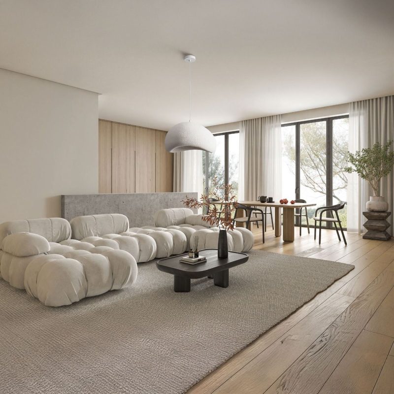 Modern living room with a white tufted sectional sofa, round dark coffee table, and large glass doors with sheer curtains. Note: concise, informative description of the scene's key elements.