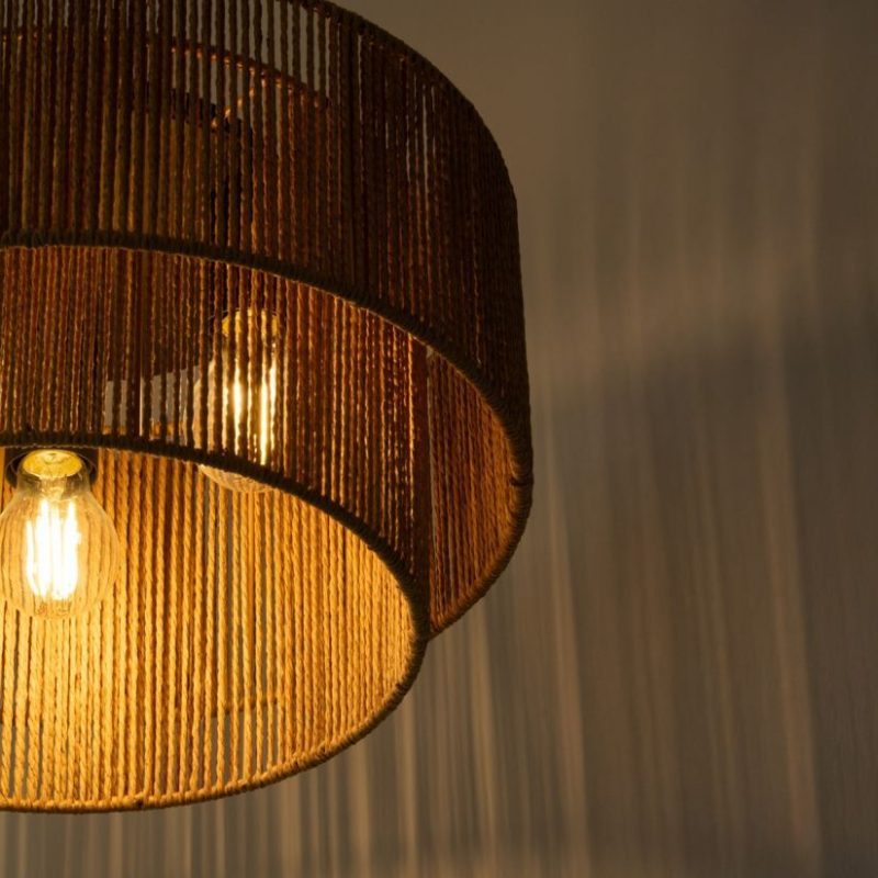 Woven rattan pendant lamp with a warm glowing bulb inside.