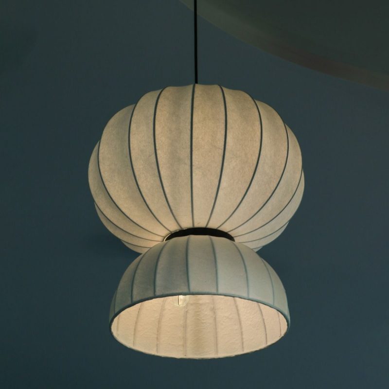 Two pale blue paper lanterns hang from the ceiling, one atop another, softly lit from within against a dark teal background.
