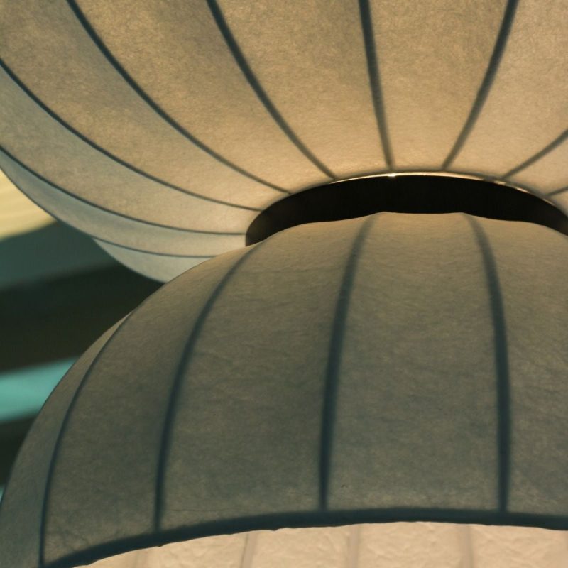 Close-up of overlapping round paper lamp shades with dark seam lines, lit from behind