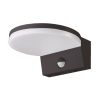 Outdoor wall-mounted light fixture with a white circular shade and a dark rectangular mounting base, featuring a motion sensor cap.
