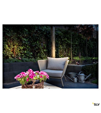 Cozy outdoor patio with a beige cushioned chair, a pink flower basket on a table, and a watering can nearby.