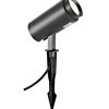 Black outdoor garden spotlight on a ground stake with an adjustable cylindrical head for landscape lighting.