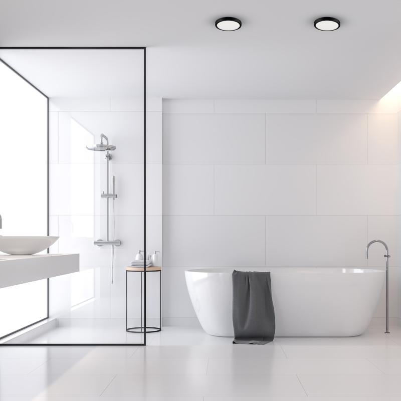 Minimalist white bathroom with a freestanding tub, glass-walled shower, and a gray towel draped over the tub edge.