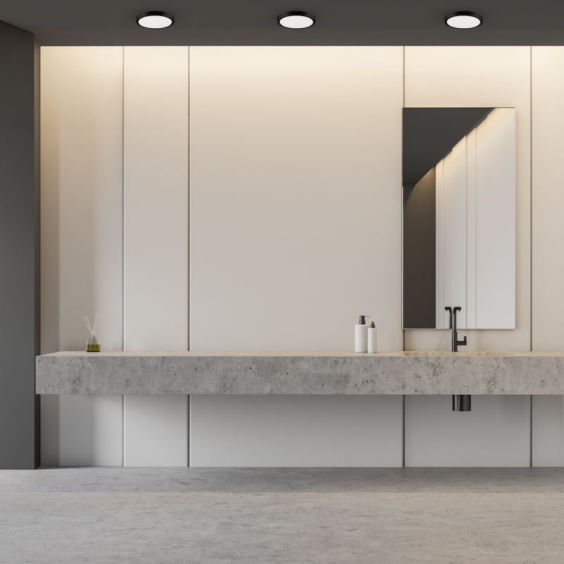 Minimalist bathroom with a long concrete vanity, beige cabinets, and a rectangular mirror.
